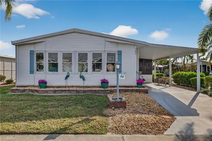 Manufactured / mobile home with concrete driveway, a sunroom, a front yard, and a carport