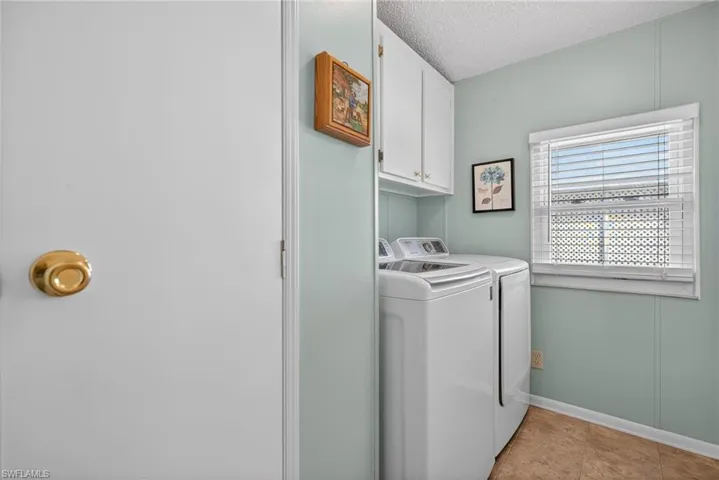 Washroom featuring cabinet space, washing machine and dryer, and a textured ceiling