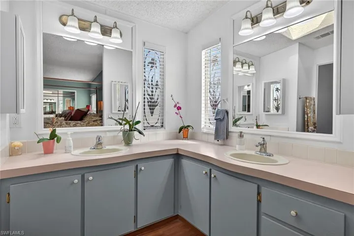 Full bathroom with a textured ceiling, double vanity, connected bathroom, and dark wood-style floors
