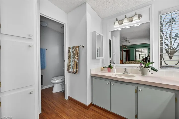 Bathroom with a textured ceiling, vanity, dark wood finished floors, and ceiling fan