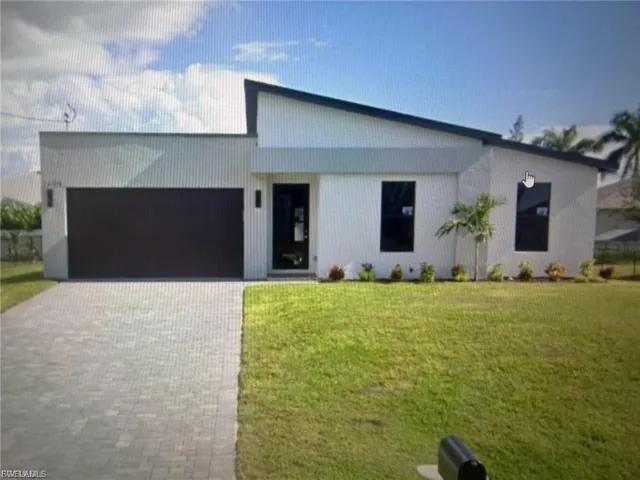 View of front of property with decorative driveway, a front lawn, and an attached garage
