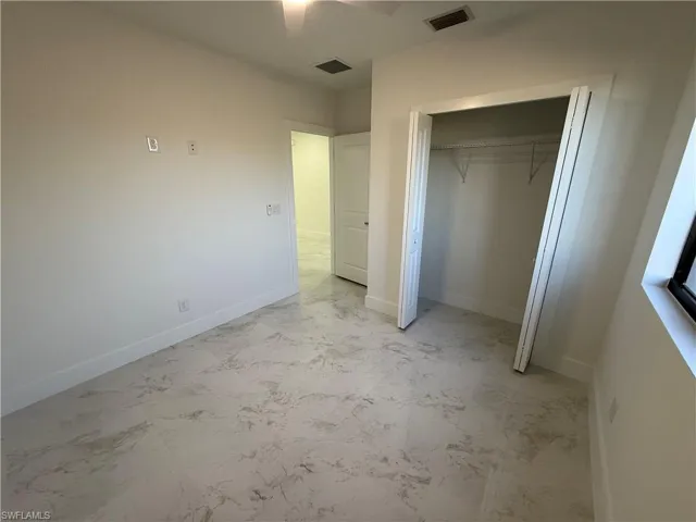 Unfurnished bedroom with light marble finish floors, a closet, and ceiling fan