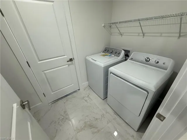 Laundry room featuring light marble finish flooring and independent washer and dryer