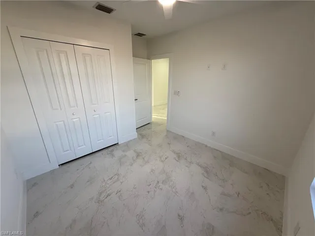 Unfurnished bedroom featuring a closet, ceiling fan, and light marble finish flooring