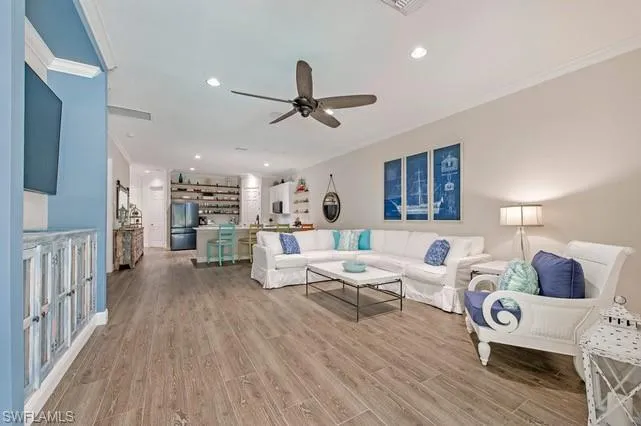 Spacious living area featuring wood-finish flooring, crown molding, and recessed lighting