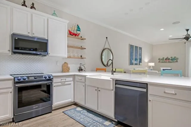 Modern kitchen featuring white cabinetry, quartz countertops, a farmhouse sink with a gooseneck faucet, a white scallop-tile backsplash, and wood-finish flooring