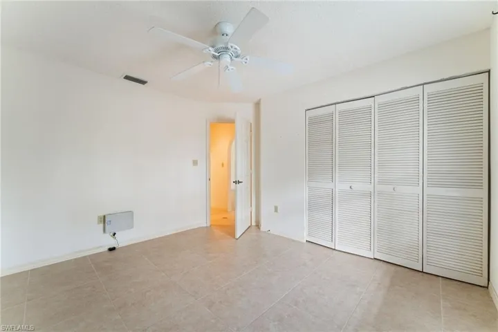 Unfurnished bedroom featuring ceiling fan, a closet, and light tile patterned floors