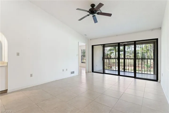 Empty room with light tile patterned flooring, a ceiling fan, and high vaulted ceiling