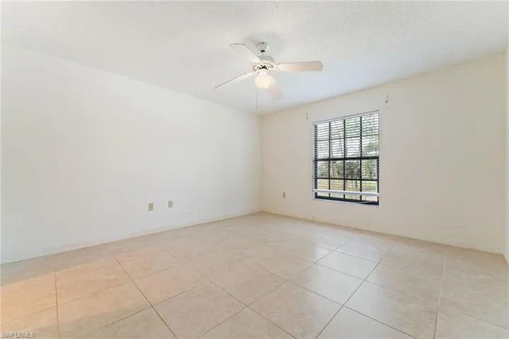 Unfurnished room featuring a textured ceiling, light tile patterned floors, and a ceiling fan