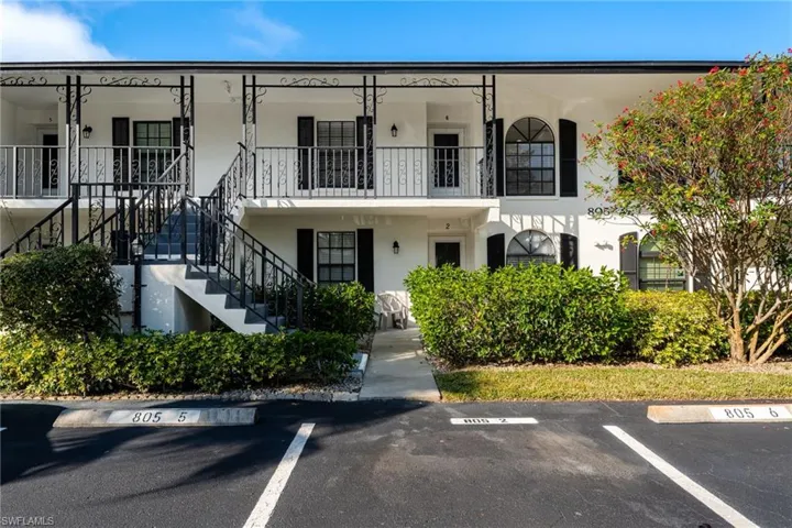 View of building exterior featuring stairs and uncovered parking