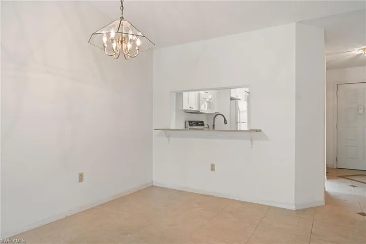 Unfurnished dining area featuring a chandelier and baseboards