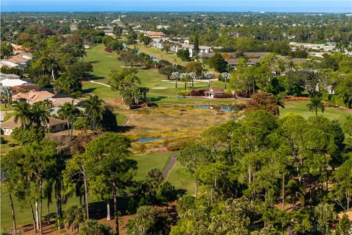 Aerial view of property and surrounding area with nearby suburban area, a large body of water, and a golf club