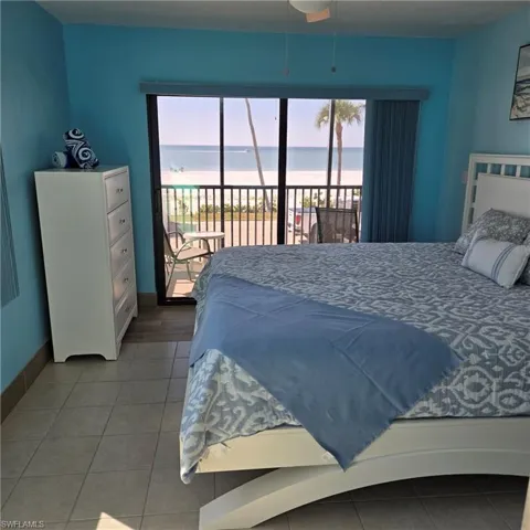 Bedroom with access to outside, a water view, multiple windows, and tile patterned floors