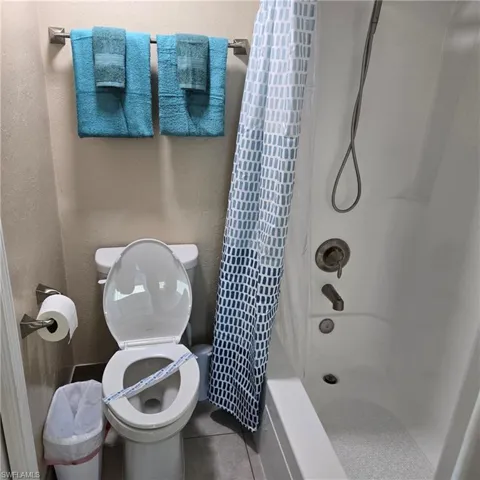 Full bath featuring shower / tub combo with curtain, tile patterned floors, and a textured wall
