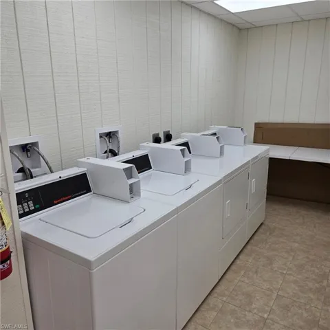 Communal laundry room featuring washing machine and dryer and a paneled ceiling