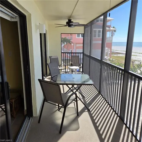 Balcony with a ceiling fan and view of water and beach