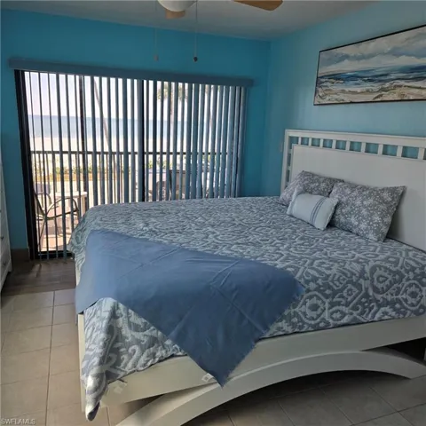 Tiled bedroom with multiple windows, access to exterior, and ceiling fan