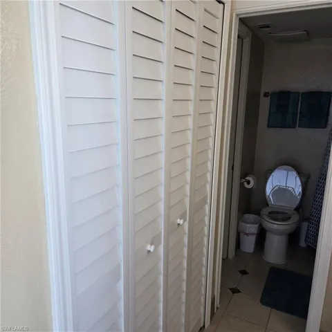 Bathroom with a closet, light tile patterned floors, and a textured wall