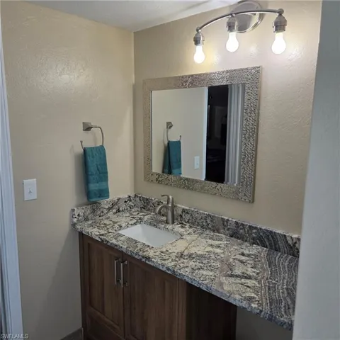 Bathroom with a textured wall and vanity