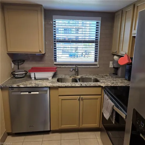 Kitchen featuring appliances with stainless steel finishes, light stone counters, and light tile patterned flooring