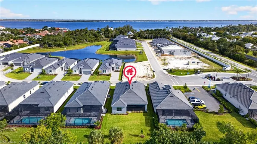Aerial view of the property and its surrounding community, featuring a water view, a pool with a screened enclosure, a private driveway, and a well-maintained lawn