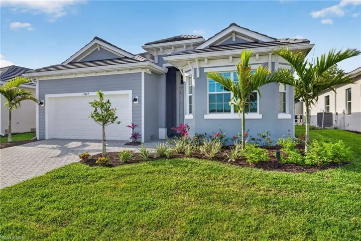 The property features a well-maintained lawn, a paved driveway, and a two-car garage