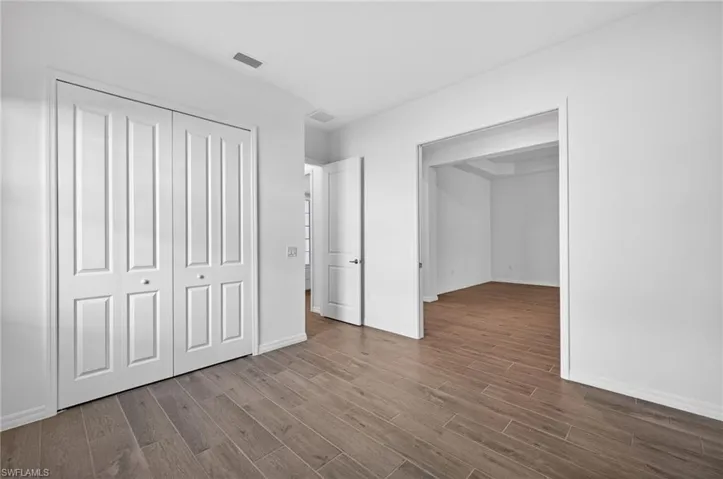 Bedroom/Den featuring plank-style flooring, a double bi-fold door closet, and an open doorway leading to an additional space