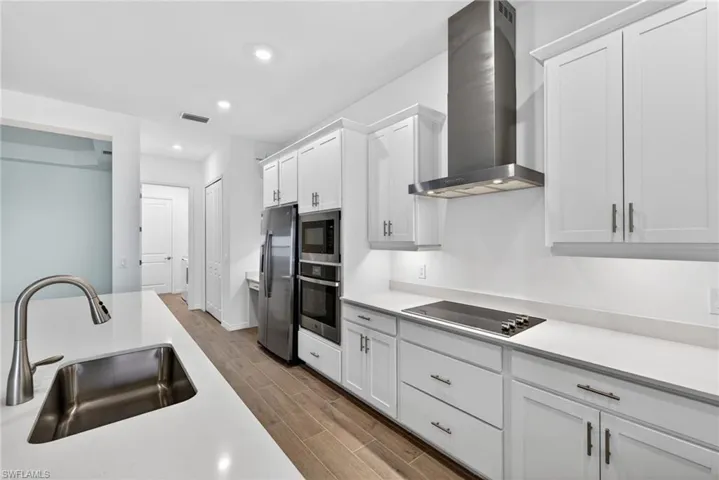 Contemporary kitchen featuring white cabinetry, stainless steel appliances, a large island with an undermount sink, and recessed lighting