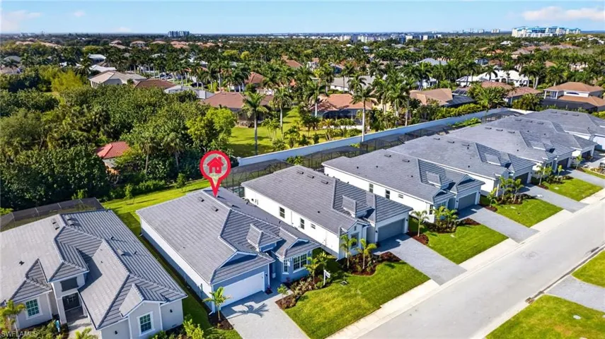 Aerial view of the property and surrounding neighborhood, featuring a gray tile roof, an attached garage, and a driveway