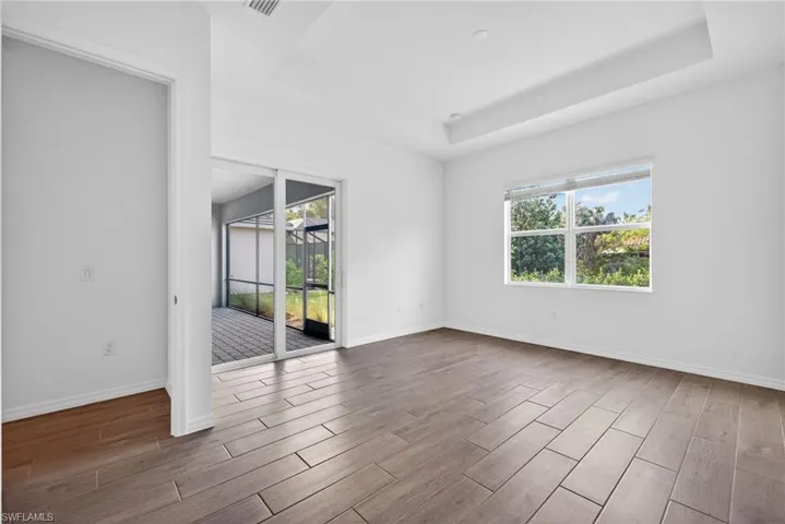 Primary Bedroom features tile flooring, white walls, and lanai access