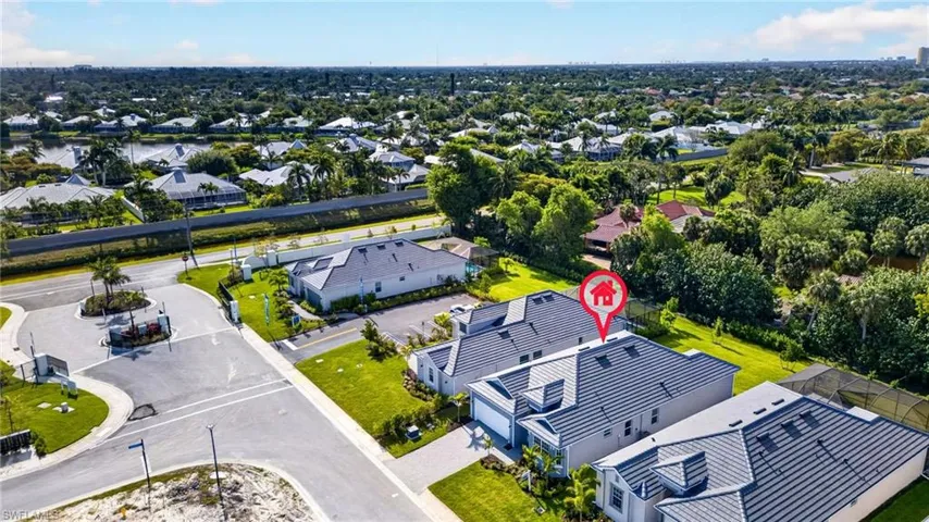 Aerial view showcasing the property with a grey tile roof, an attached garage, and a lush green lawn
