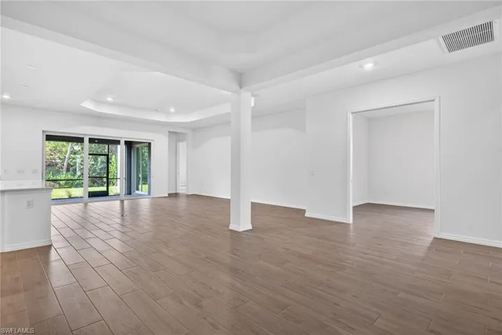Expansive open-concept living area featuring light wood-look tile flooring, white walls, and a recessed ceiling