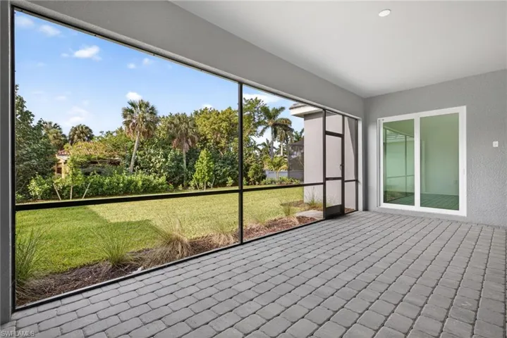 Expansive screened patio featuring paver flooring and views of the surrounding green space and trees