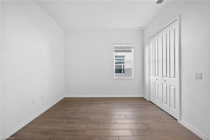 Bedroom/Den featuring clean white walls, wood-look flooring, and a window with blinds