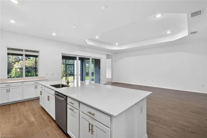 Spacious kitchen featuring an island with a sink, white cabinetry, and light-colored countertops