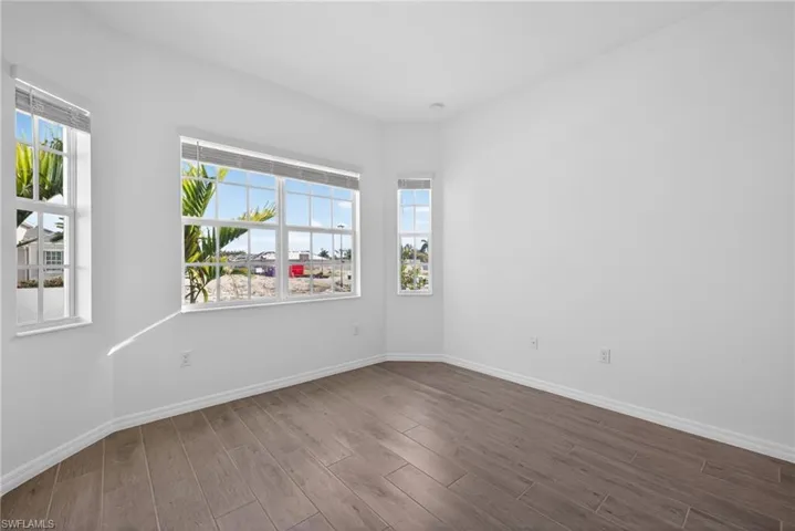 This room features light-colored walls, wood-look flooring, and multiple windows with white frames