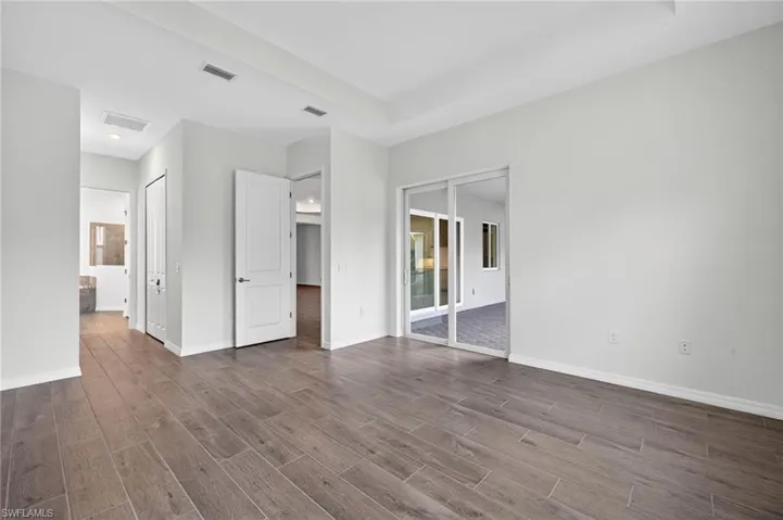 Primary Bedroom with wood-style tile flooring, white walls, and a tray ceiling