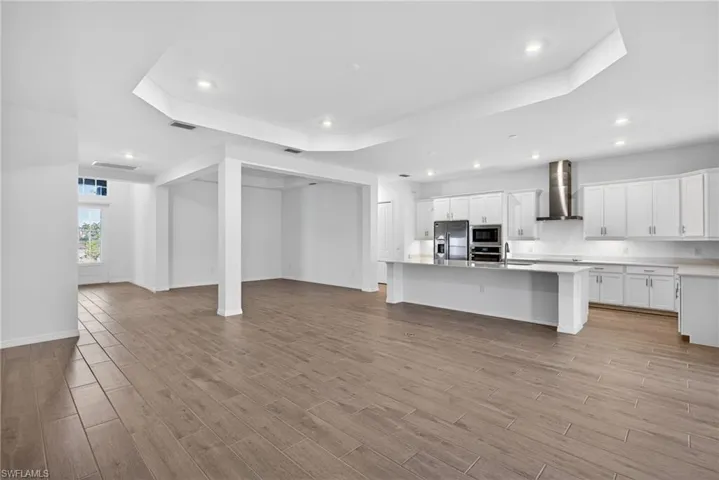 Expansive open concept living area featuring wood-look tile flooring, white walls, and recessed lighting
