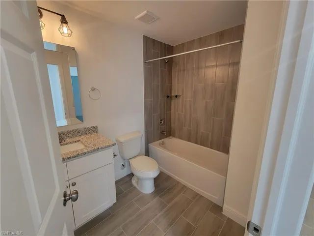 Full bath with vanity, wood finish floors, and shower / bath combination