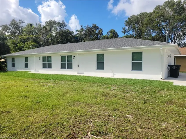 View of front of home with a front lawn, a shingled roof, and stucco siding