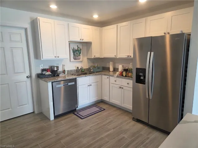 Kitchen featuring stainless steel appliances, white cabinets, dark stone counters, recessed lighting, and wood tiled floors