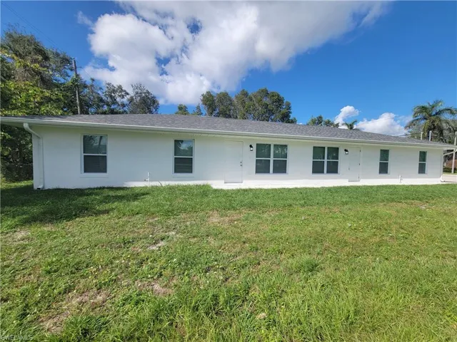 Rear view of property featuring a yard and stucco siding