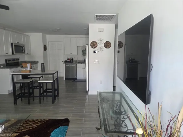 Kitchen featuring white cabinetry, wood tiled floors, stainless steel appliances, and dark stone countertops