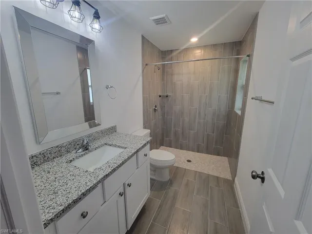 Bathroom with vanity, a stall shower, and wood finish floors