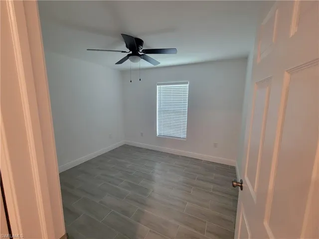 Unfurnished bedroom featuring ceiling fan and wood tiled floors