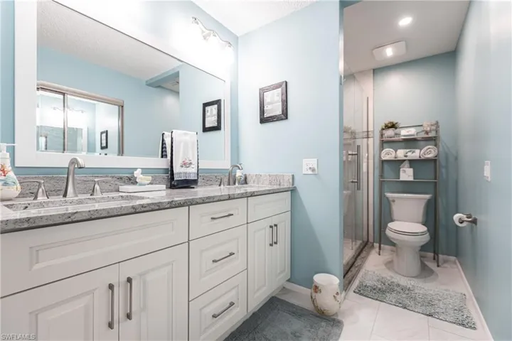 Bathroom with double vanity, a stall shower, light tile patterned floors, and a textured ceiling
