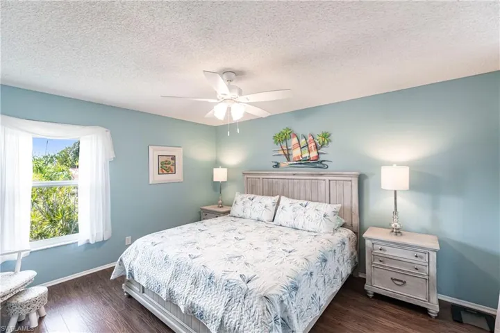Bedroom with dark wood-style flooring, a textured ceiling, and a ceiling fan