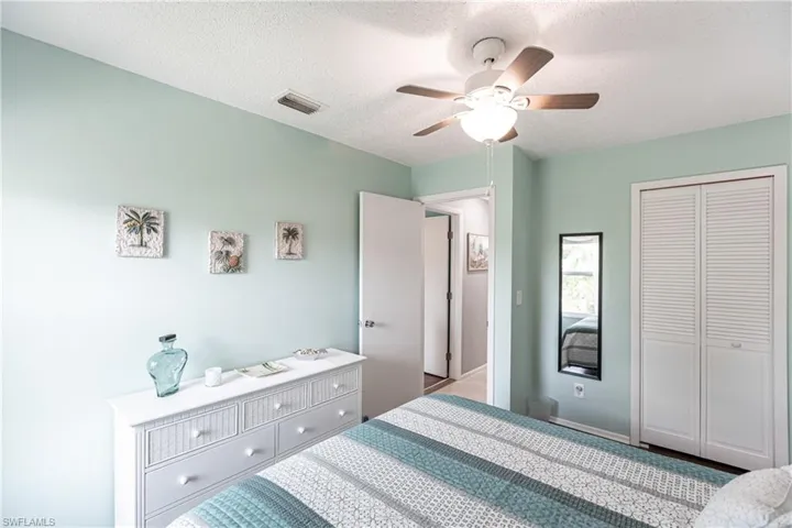 Bedroom featuring a textured ceiling, a closet, a ceiling fan, and carpet