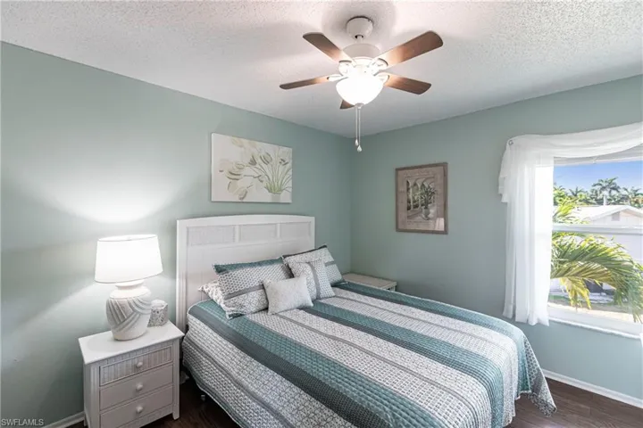 Bedroom featuring dark wood finished floors, a ceiling fan, and a textured ceiling