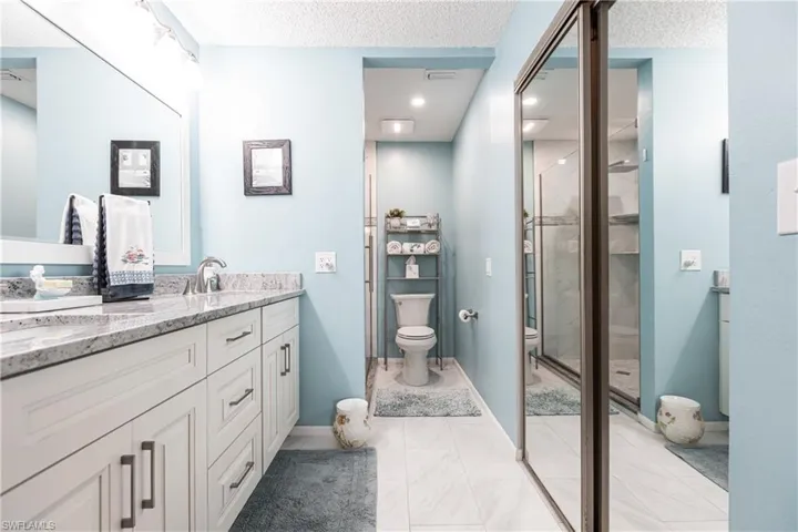 Full bath featuring double vanity, a textured ceiling, a stall shower, and light tile patterned floors